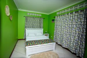 a green room with a bed and a curtain at The Mbuya Residence in Kampala