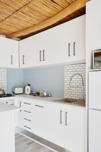 a white kitchen with white cabinets and a wooden ceiling at Little Willow Brooke in Franschhoek