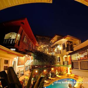 an outdoor patio with a pool and buildings at night at Coron Bancuang Mansion in Coron