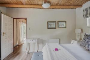 a bedroom with a white bed with a pink teddy bear on it at Little Willow Brooke in Franschhoek