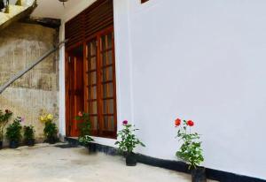 a white building with a red door and flowers at Black And White Kandy Guest House 01 in Kandy