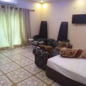 a room with a bed and two chairs and a television at Hotel Versa Appartments lodges Gulberg3 in Lahore