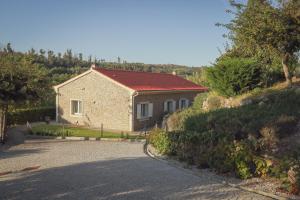 uma pequena casa com um telhado vermelho numa estrada em I Love Dão Casas Da Fraga em São Gemil