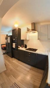 een keuken met zwarte kasten en een zwarte koelkast bij King St Cosy - wood stove & ice maker in Loughborough