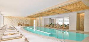 a pool with chaise lounge chairs and a swimming pool at Ikos Porto Petro in Portopetro