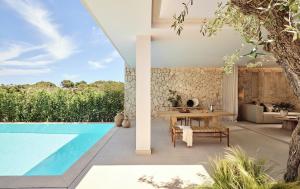 an outdoor patio with a table and a swimming pool at Ikos Porto Petro in Portopetro