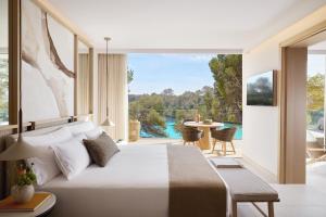 a bedroom with a bed and a balcony with a table at Ikos Porto Petro in Portopetro