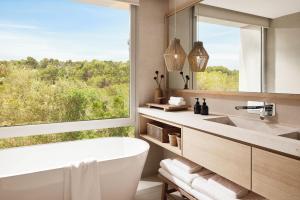 a bathroom with a tub and a large window at Ikos Porto Petro in Portopetro