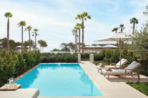 an image of a swimming pool with chairs and an umbrella at Ikos Porto Petro in Portopetro