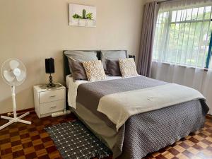 um quarto com uma cama grande e uma janela em Lovely 2 bed apartment with garden - 2047 em Harare