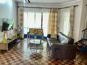uma sala de estar com um sofá de couro e uma mesa em Lovely 2 bed apartment with garden - 2047 em Harare