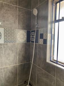 a shower with a shower head in a bathroom at Lovely 2 bed apartment with garden - 2047 in Harare