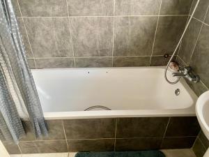 a bathroom with a white bath tub next to a sink at Lovely 2 bed apartment with garden - 2047 in Harare