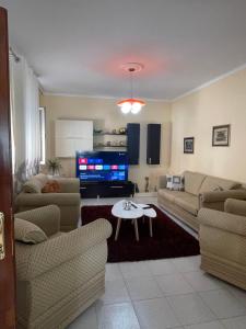 uma sala de estar com sofás, uma mesa e uma televisão em Guest house tirana em Tirana