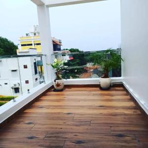 a balcony with a wooden floor and two potted plants at Paradise Breeze Inn in Kottakupam