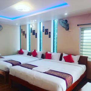 een slaapkamer met 2 bedden en rode kussens bij Paradise Breeze Inn in Kottakupam