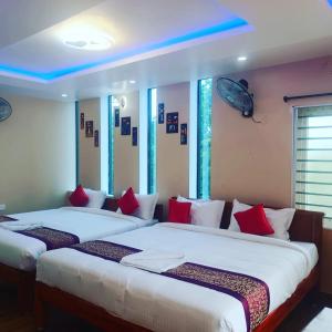 Duas camas num quarto com almofadas vermelhas e brancas em Paradise Breeze Inn em Kottakupam