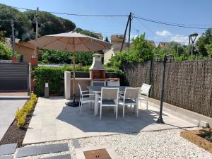 un patio con mesa, sillas y sombrilla en Casa parque Natural Montseny con piscina, barbacoa y Chimenea en San Antonio de Vilamajor