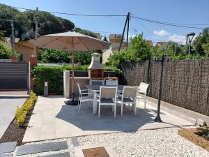 a patio with a table and chairs and an umbrella at Cerca de Barcelona, y entre tres Parques Naturales, casa de 4 habitaciones y 2 baños con piscina, barbacoa y chimenea in San Antonio de Vilamajor