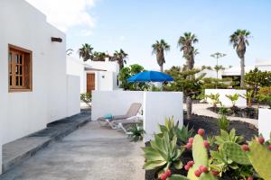 a patio with a chair and an umbrella and some plants at Casa Aloe in Haría