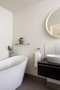 a bathroom with a tub and a sink and a mirror at Quantock Barn in Monkton