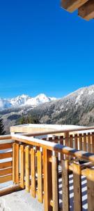 uma varanda de madeira com vista para as montanhas cobertas de neve em Les Gentianes em Saint-François-Longchamp