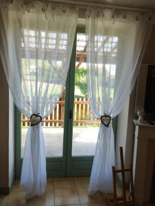 un par de cortinas blancas delante de una puerta en Au nid d'hirondelles, en Selles