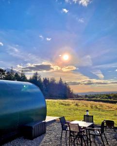 a picnic table and chairs with the sun in the sky at Forth Mountain Glamping in Ballintlea