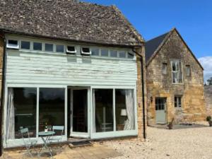 an old building with large glass doors in front of it at Pass the Keys Hare Cottage wonderful views and parking in Moreton in Marsh