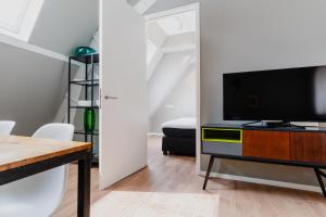 a living room with a television on a dresser with a table at Apartments De Hallen in Amsterdam