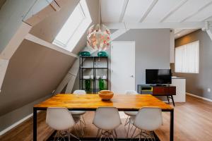 Un comedor con una mesa de madera y sillas blancas. en Apartments De Hallen, en Ámsterdam