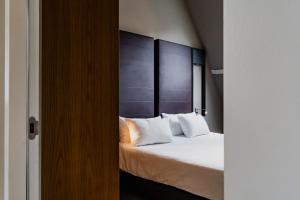 a bedroom with a bed with a headboard and white pillows at Apartments De Hallen in Amsterdam