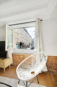 einem weißen Stuhl vor einem Fenster in der Unterkunft MyKeypers - Deluxe Flat 6P - St Germain des Près Café de FLORE in Paris