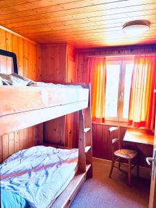 ein Etagenbett in einer Hütte mit einem Tisch und einem Stuhl in der Unterkunft Chalet Tobeleck - CharmingStay in Flumserberg