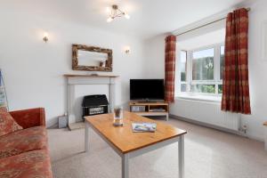 un salon avec une table basse et une télévision dans l'établissement Oaklands - Lovely Cottage Walk to Beach, à Saundersfoot