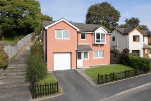 une maison rouge avec un garage blanc dans l'établissement Oaklands - Lovely Cottage Walk to Beach, à Saundersfoot