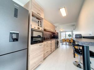 a kitchen with stainless steel appliances and wooden cabinets at SAGLIO - Neuf - Parking - Tram - Spa in Strasbourg