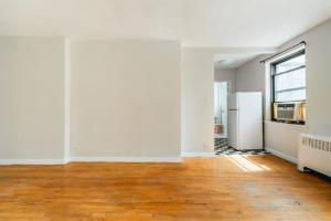 una sala de estar vacía con paredes blancas y suelo de madera. en Apartment 1333: East Village, en Nueva York