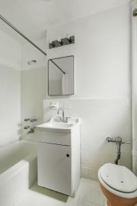Baño blanco con lavabo y aseo en Apartment 1333: East Village, en Nueva York
