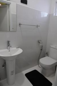 a white bathroom with a sink and a toilet at Palm Grove in Colombo