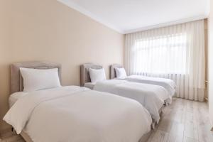 a room with three beds with white sheets and a window at Flat with Balcony 3 min to Public Transportation in Istanbul