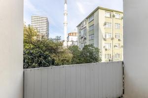 a white fence in front of buildings with a tv tower at Flat with Balcony 3 min to Public Transportation in Istanbul