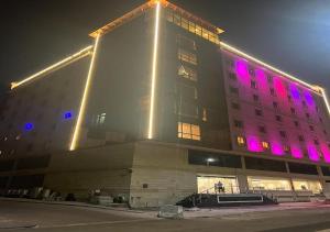 un edificio con luces púrpuras en el lateral. en فندق الفرسان en Yeda