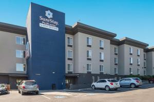 a building with cars parked in a parking lot at SureStay Plus Hotel by Best Western SeaTac Airport in SeaTac