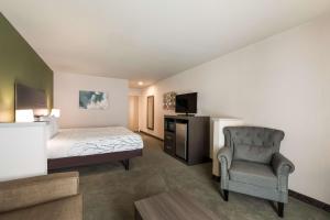 a hotel room with a bed and a chair at SureStay Plus Hotel by Best Western SeaTac Airport in SeaTac