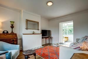 uma sala de estar com um sofá e uma televisão em Windrush Cottage em Long Hanborough