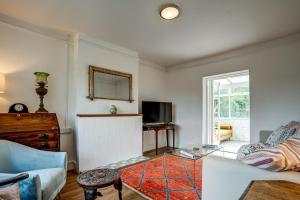 a living room with a couch and a tv at Windrush Cottage in Long Hanborough