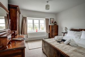 um quarto com uma cama, uma cómoda e uma janela em Windrush Cottage em Long Hanborough