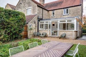 a patio with a table and chairs in front of a house at Windrush Cottage in Long Hanborough