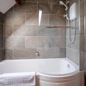een badkamer met een wit bad en een douche bij Pass the Keys Pheasant Cottage Stunning peaceful home parking in Moreton in Marsh